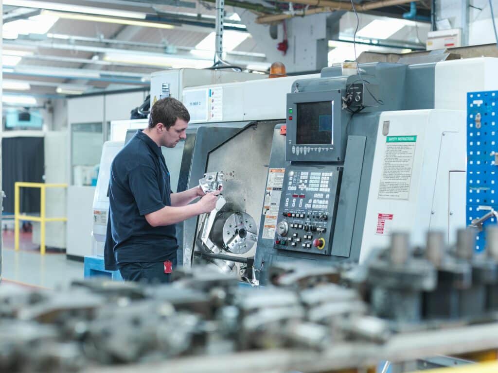 Arbeiter prüft Teile auf einer CNC-Drehmaschine in einer Maschinenbau Firma